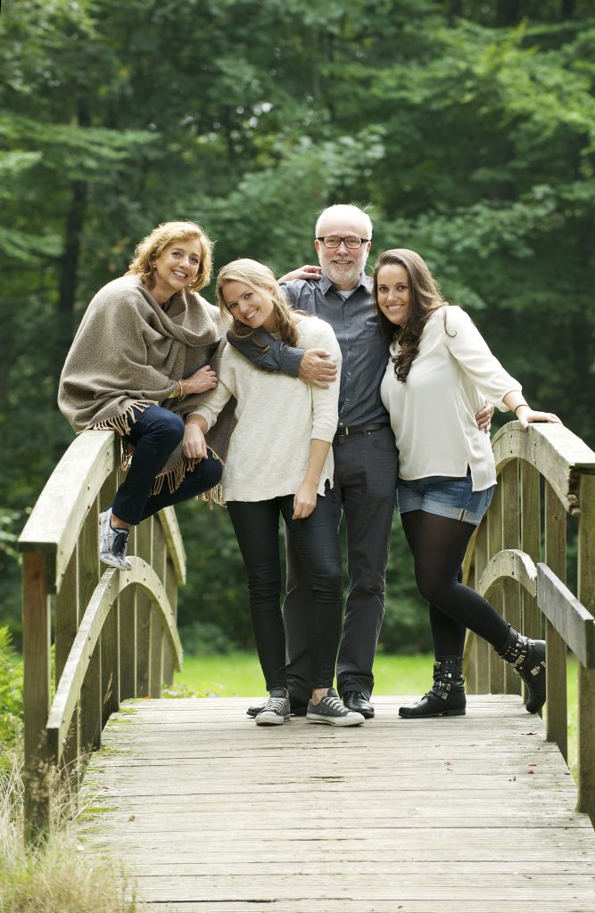 Happy family standing together on a bridge in the forest