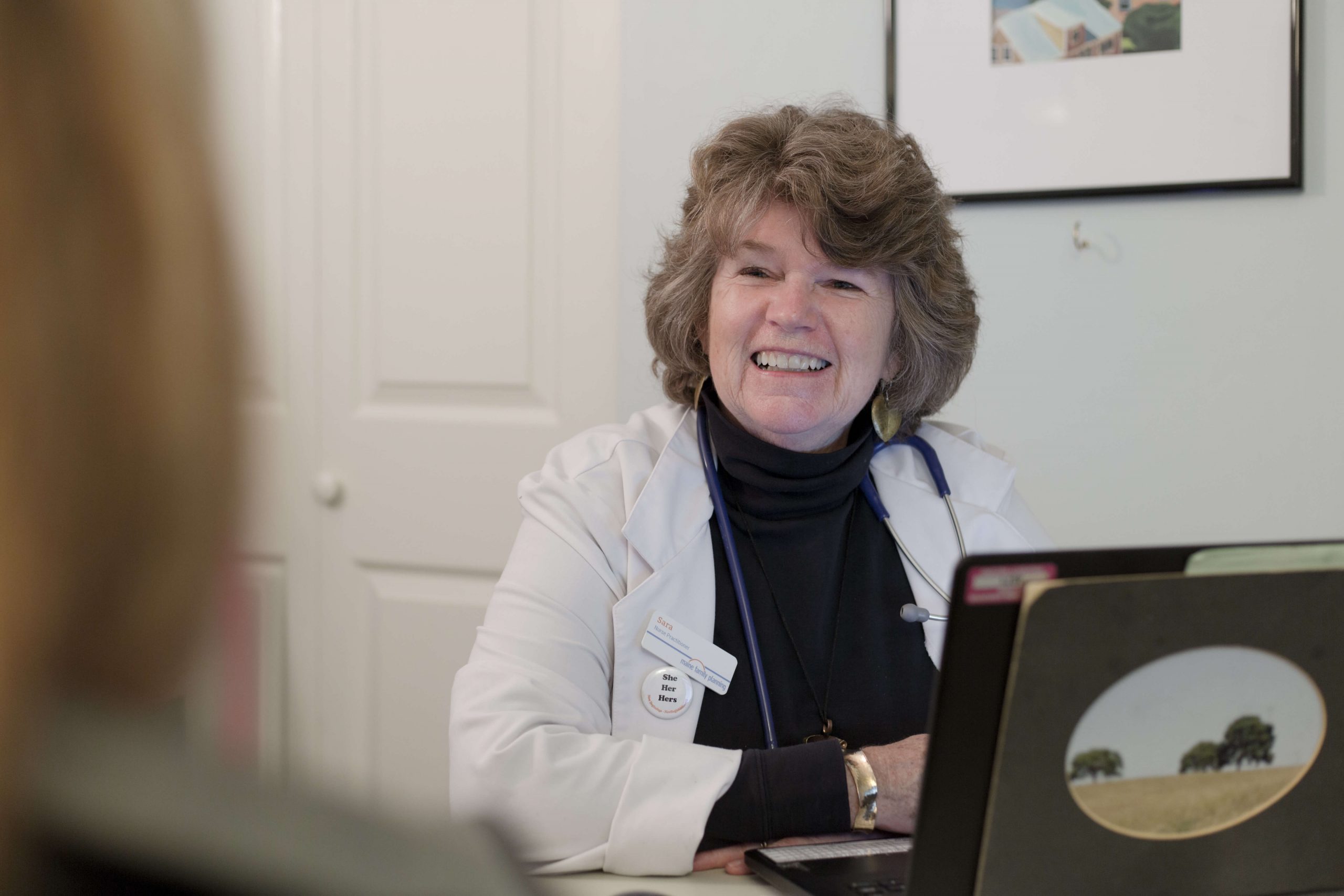 An MFP nurse practitioner sitting in front of an open laptop used for telehealth appointments.