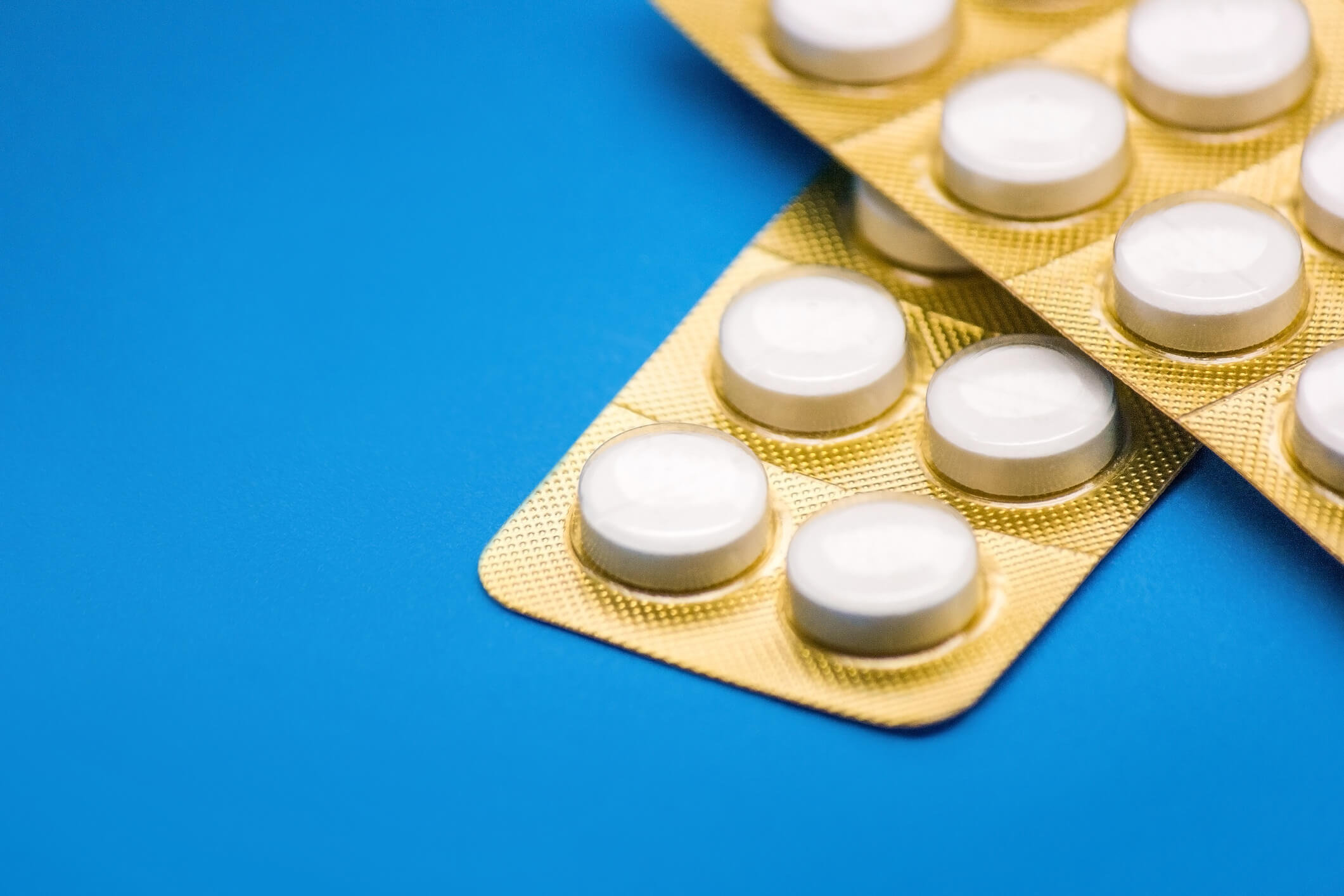 white pills with golden blister pack on a blue background close-up